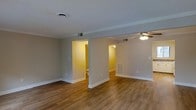 Located at 600 S Churton St in Hillsborough, NC, this two-story property offers a well-organized layout designed for comfortable everyday living. The main living area is defined by rich hardwood-style flooring that runs throughout, complemented by neutral gray walls and crisp white baseboards that create a clean, cohesive aesthetic. A ceiling fan with integrated lighting provides both comfort and illumination, while multiple doorways connect the open living space to adjacent rooms, allowing for a natural flow throughout the home. Visible HVAC vents integrated into the walls and floors reflect a thoughtfully designed climate control system. The space benefits from warm ambient lighting in the adjoining rooms, which feature the same consistent flooring and color palette, lending a sense of unity across the interior. The open passage between rooms enhances the sense of spaciousness, making the layout feel connected and accessible. With its understated finishes, functional design, and multi-level configuration, this Hillsborough property offers a straightforward and versatile living environment suited to a variety of needs.
