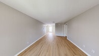 This single-floor residence offers a clean, modern aesthetic throughout its thoughtfully arranged layout, encompassing two bedrooms, two bathrooms, a living room, kitchen, and a closet. Light-toned luxury vinyl plank flooring runs consistently throughout the home, complemented by neutral gray walls and crisp white trim, creating a bright and cohesive atmosphere.

The spacious living area is open and airy, benefiting from natural light filtering through a front-facing window. The entry foyer features a paneled front door alongside an additional window, adding to the welcoming feel of the space.

The galley-style kitchen is well-equipped with white shaker cabinets, light granite-style countertops, stainless steel appliances including a refrigerator, electric range, and dishwasher, as well as a skylight that enhances the sense of brightness in the space.

The generously sized primary bedroom includes a ceiling fan with light fixture and a window overlooking an outdoor balcony or patio area. The second bedroom is equally comfortable with ample natural light.

Both bathrooms are finished consistently, each featuring a tub-shower combination with a matte black handheld showerhead, a window with blinds for natural light and privacy, light countertops, and wood-look flooring that ties seamlessly to the rest of the home.