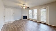 Located at 907 Galaxy Dr in Jackson, Tennessee, this single-floor residence offers a well-organized layout designed for comfortable everyday living. The living room serves as a central gathering space, featuring rich hardwood-style flooring, a ceiling fan with light fixture, a tile-surround fireplace, and large windows paired with a glass-panel door that fill the room with natural light and provide outdoor views. The galley-style kitchen is efficiently designed with ample white upper cabinetry, sleek dark lower cabinets, marble-look countertops, a full suite of black appliances including a refrigerator, electric range, microwave, and dishwasher, and durable wood-look flooring. The bedrooms are finished with plush carpeting, ceiling fans or flush-mount lighting, and windows that allow natural light throughout. At least one bedroom features access to a dedicated walk-in closet. Two full bathrooms are present, each appointed with marble-look countertops, single-sink vanities, tiled flooring, and shower-tub combinations. A dedicated in-unit laundry room with wood-look flooring and shelving above accommodates a full-size washer and dryer. Textured ceilings and neutral tones throughout create a clean, move-in-ready atmosphere.