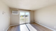 Located at 2143 Bollman Drive in Sheboygan, Wisconsin, this well-appointed one-bedroom, one-bathroom unit offers a thoughtfully organized single-floor layout. Light-toned luxury vinyl plank flooring runs throughout the space, complementing the warm beige walls and crisp white trim for a clean, cohesive aesthetic.

The living room is the centerpiece of the unit, bathed in natural light streaming through a sliding glass door that opens to a private balcony with decorative railing and pleasant outdoor views. A wall-mounted air conditioning unit ensures year-round comfort. Textured ceilings add a classic architectural touch throughout.

The kitchen is notably updated, featuring white shaker-style cabinetry with matte black hardware, a subway tile backsplash, light granite countertops, a black undermount sink, and stainless steel appliances, including a refrigerator and range with a ventilation hood. Recessed lighting keeps the space bright and functional.

The bedroom offers a comfortable footprint with a large double-door closet for ample storage, a bright window overlooking the outdoors, and easy access to the full bathroom. The bathroom is clean and modern, equipped with a tub-shower combination, white vanity with storage, and light wood-tone flooring that ties the space together harmoniously.