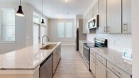Located at 3915 William E Murray Blvd in Charleston, SC, this well-designed single-story home offers three bedrooms and two bathrooms within a thoughtfully laid-out floor plan. A central hallway connects the main living areas, finished with light wood-style flooring and clean white trim throughout.

The open kitchen and living room serve as the heart of the home. The kitchen is equipped with stainless steel appliances — including a full-size refrigerator, electric range, and built-in microwave — complemented by granite countertops, a deep undermount sink, textured light-wood cabinetry, and a tiled backsplash. Pendant lighting and large windows allow natural light to fill the space.

The primary bedroom is a comfortable retreat featuring hardwood-style flooring, a ceiling fan, and multiple windows that bring in abundant natural light. The two secondary bedrooms are carpeted and finished in neutral tones, offering flexibility for various uses.

The primary bathroom features a double-sink vanity with granite countertops and warm wood cabinetry. The second bathroom includes a full tub-shower combination with tiled surround. Both bathrooms are finished with light wood-style flooring and brushed nickel or gold hardware. A dedicated closet and hallway complete the floor plan, making this home as functional as it is welcoming.