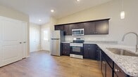 This single-floor residence in Maumee, Ohio offers a thoughtfully designed layout across a comfortable footprint. The open-concept kitchen and living area serves as the heart of the home, featuring rich dark-espresso cabinetry, granite-look countertops, and a full suite of stainless steel appliances including a refrigerator, range, microwave, and dishwasher. Recessed lighting and pendant fixtures illuminate the kitchen, while warm wood-tone luxury vinyl plank flooring extends throughout the main living areas, creating a cohesive and inviting atmosphere.

The living room is bright and airy, highlighted by a ceiling fan, sliding glass door with vertical blinds, and views of the outdoors. A connected dining or flex space flows seamlessly from the kitchen, enhancing the open feel of the layout.

Both bedrooms are carpeted and equipped with ceiling fans and natural light from windows. The generously sized primary bedroom connects to a full bathroom featuring a granite-topped vanity with dark cabinetry, a tub-shower combo with white tile surround, and wood-tone flooring. Three closets, including a spacious walk-in with wire shelving, provide ample storage throughout the residence. Neutral warm-toned walls throughout contribute to a clean, move-in-ready aesthetic.