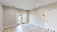 Located at 19448 Northridge Dr in Northville, MI, this thoughtfully designed single-floor residence offers a clean, modern aesthetic throughout. Light hardwood-style flooring flows seamlessly across the main living areas and hallway, complemented by neutral warm-beige walls and recessed lighting that create a bright, welcoming atmosphere.

The open-concept area integrates the living room, dining room, and kitchen into one cohesive space. The kitchen is well-appointed with light wood cabinetry, stainless steel appliances including a refrigerator, gas range, microwave, and dishwasher, along with light quartz countertops and a classic white subway tile backsplash. The living area features French doors that open to an outdoor view, filling the space with natural light.

The spacious primary bedroom is finished with plush carpet flooring and includes a window with outdoor views. Three closets provide generous storage throughout the unit, including a walk-in closet equipped with built-in shelving and hanging rods.

The full bathroom offers a modern floating vanity with a wood-toned base, a framed mirror, and a combination tub and shower. An in-unit laundry area adds everyday convenience. The hallway connects all rooms efficiently, reinforcing the unit's functional and well-organized layout.