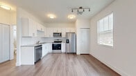 Located on Allure Circle in Orange City, FL, this one-bedroom, one-bathroom unit offers a thoughtfully designed single-floor layout that maximizes every inch of its compact footprint. The open-concept living and kitchen area is bathed in natural light, with wood-look flooring flowing throughout and a ceiling fan overhead adding to the airy atmosphere. French doors lead to a private balcony, bringing in additional light and outdoor views.

The kitchen is a standout feature, outfitted with crisp white shaker cabinetry, subway tile backsplash, stone countertops, and a full suite of stainless steel appliances including a refrigerator with ice maker, electric range, microwave, and dishwasher. A louvered closet door nearby provides additional storage convenience.

The bedroom is generously sized with plush carpeting, a ceiling fan, and a bright window with a neighborhood view. It connects directly to a well-organized walk-in closet with built-in shelving. Two additional closets provide ample storage throughout the unit.

The bathroom is clean and modern, featuring a white vanity with stone countertop, a large mirror, and a tiled tub-shower combination. Wood-look flooring and a natural light window complete the space with a fresh, polished feel throughout.