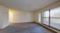 This single-floor unit on Wornall Road in Kansas City, MO offers a practical and comfortable layout across several well-defined spaces. The expansive living area is finished with neutral-toned carpet and features a pair of sliding glass doors alongside an adjacent window, flooding the room with natural light and providing direct access to a private balcony. The balcony overlooks lush, mature trees, offering a serene outdoor retreat framed by a stone ledge and black metal railing.

The kitchen is equipped with warm oak cabinetry offering generous storage, dark countertops, a white refrigerator, and an electric range with overhead ventilation. Wood-look flooring grounds the space with a classic, easy-to-maintain surface.

The bedrooms are carpeted and bright, each featuring textured ceilings and ample wall space. One bedroom includes a louvered closet and connects to adjacent hallway access, while another benefits from a tall, narrow window that introduces additional natural light.

The bathroom area includes a vanity with oak cabinetry and dark countertop, louvered closet doors for storage, and a full tub-shower combination enclosed in a glass sliding door. An additional smaller room with wood-look flooring offers versatile use as an office or storage space.