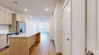 This thoughtfully designed one-bedroom, one-bathroom unit offers a bright and modern living experience across a single floor. Warm-toned hardwood-style flooring flows seamlessly throughout, complementing the clean white walls and recessed lighting that keep the space feeling open and inviting.

The contemporary kitchen is a standout feature, showcasing light wood flat-panel cabinetry extending to the ceiling, sleek granite countertops with a white subway tile backsplash, and a full suite of stainless steel appliances including a French door refrigerator, electric range with microwave, and dishwasher. A central island with matching granite provides additional prep space and casual seating potential.

The open living area is bathed in natural light from a large sliding glass door that opens to an outdoor view, while recessed lighting ensures the space is well-lit at any hour. The bedroom features a ceiling fan, a generous window with neighborhood views, and direct access to the full bathroom. The bathroom is elegantly appointed with a soaking tub, light wood vanity, and granite countertop.

Exceptional storage is a defining characteristic of this unit, with five closets throughout — including a spacious walk-in fitted with wire shelving — plus an in-unit laundry area, making this a highly functional and well-organized living space.