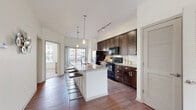 Located at 345 E Deshler Ave in Columbus, Ohio, this two-story, two-bedroom, two-bathroom home offers a well-designed layout across two levels. The lower level serves as the entry point, featuring a welcoming entrance and access to an attached garage. The upper level hosts the main living areas, where rich hardwood flooring flows throughout the open-concept kitchen and adjoining spaces. The kitchen is a standout feature, boasting dark espresso cabinetry, granite countertops, a white center island with bar seating, pendant lighting, track lighting, a subway tile backsplash, and black appliances. A balcony sits just off the kitchen, offering an outdoor retreat. The living room is bright and inviting, with large windows that bring in natural light and plush carpeting underfoot. Both bedrooms are generously sized, carpeted, and filled with natural light from well-placed windows, with the primary bedroom offering ample closet space. The primary bathroom features a double-sink vanity with dark cabinetry, tile flooring, and a walk-in closet. The second bathroom includes a tub-shower combination. Additional conveniences include a laundry area, pantry, and multiple closets throughout.