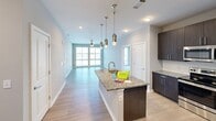 Located at 2120 North Brevard Street in Charlotte, NC, this 2-bedroom, 1-bathroom residence offers a thoughtfully designed single-floor layout with contemporary finishes throughout. The open-concept kitchen is a standout feature, showcasing dark espresso cabinetry, granite countertops, stainless steel appliances including a range, microwave, and refrigerator, a subway tile backsplash, and a central island with pendant lighting overhead. The kitchen flows seamlessly into the living area, which is bathed in natural light from large windows. Both bedrooms are carpeted and feature ceiling fans and oversized sliding windows that bring in abundant natural light. The spacious primary bedroom includes its own closet with wire shelving systems for organized storage. The bathroom is well-appointed with a dual-sink granite vanity, dark wood cabinetry, a full tub and shower combination with classic subway tile surround, and wood-look flooring. Neutral gray tones and clean white trim are carried throughout the space, creating a cohesive and modern aesthetic. With two closets and a practical layout, this residence offers both comfort and functionality in the heart of Charlotte.