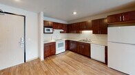 Located at 8412 22nd Ave S in Bloomington, Minnesota, this single-floor unit offers a practical and well-designed layout suited for comfortable everyday living. The open-concept living area is finished with light hardwood-style flooring that extends throughout the main spaces, creating a cohesive and bright atmosphere. Large windows allow natural light to fill the living area, enhancing the clean, neutral palette of the interior.

The kitchen is a standout feature, offering rich dark cherry cabinetry with modern hardware, light countertops, and a full suite of white appliances including a range, built-in microwave, dishwasher, and refrigerator. A double-basin sink and ample upper and lower cabinet storage make this kitchen both functional and attractive. The kitchen flows openly into the living space, ideal for everyday use.

The unit includes two carpeted bedrooms, each providing a quiet retreat. One bedroom features a window with blinds for natural light and privacy, while the other includes a built-in storage wardrobe.

Two full bathrooms serve the unit, both featuring tile flooring, a tub/shower combination, and dark wood vanity cabinetry with white countertops and a mirror. The clean, minimal design ensures a bright and functional experience throughout.