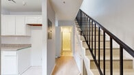 Located in Van Nuys, Los Angeles, this two-bedroom, two-bathroom home spans two floors, offering a well-organized layout designed for comfortable everyday living. The ground floor houses the main living areas, including a combined dining and living room, a kitchen, and a bathroom. Light wood flooring flows through the main living spaces, while tile flooring is featured in the kitchen and bathrooms. The kitchen is equipped with white raised-panel cabinetry, granite-style countertops, a double stainless steel sink with a window overlooking the outdoors, a gas range, and a dishwasher — providing ample functionality for home cooking. A staircase with a sleek black metal railing connects the two floors, with built-in storage tucked neatly beneath it. The upper floor contains both bedrooms, including a generously sized primary bedroom, as well as a full bathroom with a tub-shower combo featuring frosted sliding glass doors and a vanity with dark countertops. The second bathroom offers a vanity with granite-style countertops and tile flooring. Both bedrooms feature light wood flooring and neutral light-gray walls, creating a clean and versatile canvas. Three closets throughout the home provide ample storage, completing this efficient and well-appointed two-story residence.