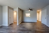 Located at 7000 Crabapple Ln in Kansas City, Missouri, this single-floor residence offers a well-designed layout with a clean, neutral aesthetic throughout. The open living area is a standout feature, showcasing durable wood-look flooring, soft neutral wall tones, and a ceiling fan that adds both function and character. A textured popcorn ceiling runs throughout the main living spaces, and a pass-through window connects the living area to the kitchen, enhancing the open feel. A sliding glass door in one of the living areas floods the space with natural light and provides direct access to the outdoors. The kitchen is equipped with white shaker-style cabinetry, light countertops, and black appliances including a refrigerator, range, and dishwasher, all set over light wood-look tile flooring. The bedroom features plush carpeting, a walk-in closet with louvered doors, and a window that brings in natural light. The bathroom is outfitted with a full tub-shower combination, a white vanity with a speckled countertop, a framed mirror, and wood-look flooring. A dedicated entry hallway with a thermostat and utility panel completes the functional layout of this well-appointed home.