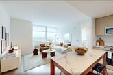 Located at 36 Journal Square Plaza in Jersey City, NJ, this well-appointed one-bedroom, one-bathroom residence offers a thoughtfully designed layout across a single floor. Light hardwood flooring flows throughout, complementing the clean, modern aesthetic defined by crisp white walls and abundant natural light.

The open-concept kitchen and living area serves as the heart of the home. The kitchen is outfitted with flat-front light wood cabinetry extending to the ceiling, stainless steel appliances, a tile backsplash, and a striking marble-topped island with seating — ideal for both cooking and casual dining. The adjacent living area is bright and airy, anchored by large floor-to-ceiling windows that frame sweeping panoramic views of the surrounding cityscape and beyond.

The bedroom continues the serene, light-filled atmosphere, featuring oversized windows with expansive views, providing a tranquil retreat. A dedicated closet and hallway entry add functional storage and flow. The bathroom is finished with large-format stone-look tile, a clean vanity with wood cabinetry, and a walk-in shower with chrome fixtures. In-unit laundry adds everyday convenience. A welcoming hallway entry with hardwood flooring completes this polished, move-in-ready residence.