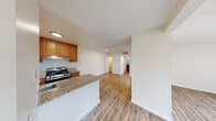 This thoughtfully designed 1-bedroom, 1-bathroom unit offers a functional and comfortable single-floor layout. The open-concept kitchen and living area creates a seamless flow, anchored by warm wood-style flooring that extends throughout the main living spaces. The kitchen is well-equipped with rich honey-toned cabinetry, granite-style countertops, a stainless steel gas range, and a built-in sink with ample counter space. Upper and lower cabinets provide generous storage, complemented by a window that brings in natural light. The kitchen opens directly into the combined living area, which features a textured ceiling and a sliding glass door leading to a private balcony with outdoor views — a standout feature that fills the space with natural light and fresh air. A dedicated hallway connects the main living area to the bedroom and bathroom. The bedroom is carpeted for comfort, features a sliding closet door, and is served by a window with vertical blinds. The bathroom is clean and functional, offering a full tub-shower combination with tile surround, a toilet, and a granite-topped vanity. Throughout the unit, neutral walls and light-toned finishes create a bright, cohesive ambiance.