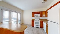 Located on Commonwealth Avenue in Allston, this single-floor unit offers a practical and well-organized layout. The living area is a standout feature, highlighted by a curved bay window that allows generous natural light to fill the space, complementing the warm hardwood floors throughout. A peninsula counter connects the living area to the kitchen, creating an open, functional flow between the two spaces.

The kitchen is well-appointed with warm-toned wood cabinetry, a classic white subway tile backsplash, and light stone-finish countertops. White appliances include an electric range with overhead microwave, a dishwasher, and a refrigerator. Light ceramic tile flooring runs throughout the kitchen, which also benefits from access to an outdoor balcony via a glass-paned door, providing additional ventilation and light.

The bedrooms feature the same hardwood flooring found in the living area, with one room offering a built-in closet with louvered doors and another equipped with a standard door closet. Windows in each bedroom provide natural light.

The bathroom is finished with white subway tile wainscoting, a window with a roller shade, a white vanity with sink, and tile flooring, maintaining a clean and bright aesthetic throughout.