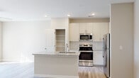 Located at 1090 Summersweet Dr in New Bern, North Carolina, this single-story residence presents a clean, modern aesthetic throughout its well-designed layout. Light wood-style flooring flows consistently across the living areas and bedrooms, complementing the neutral warm-beige and white color palette that defines the interior.

The kitchen serves as a functional centerpiece, featuring white shaker-style cabinetry with brushed nickel hardware, granite countertops with subtle veining, and a subway tile backsplash. A kitchen island with an undermount stainless steel sink adds workspace and visual interest. Stainless steel appliances—including a range, over-the-range microwave, and refrigerator—provide a polished, contemporary finish. A dedicated pantry with built-in shelving offers additional storage convenience.

The living area benefits from natural light streaming through a sliding glass door that leads to an outdoor space, creating a bright and airy atmosphere enhanced by a ceiling fan overhead. Bedrooms are generously proportioned, featuring the same wood-style flooring, ceiling fans, and ample wall space. At least one bedroom includes a dedicated walk-in closet. The bathroom is finished with a white tiled tub surround and brushed nickel fixtures, maintaining the home's cohesive, clean design sensibility throughout.