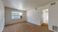 Located at 1750 Clifton Ave. in Columbus, Ohio, this single-floor unit offers a straightforward and functional layout spread across multiple rooms. The living area is finished with wall-to-wall carpet in a warm neutral tone and features crisp white walls that keep the space feeling open and bright. A window unit air conditioner and ceiling ventilation provide climate control, while a louvered closet door adds convenient built-in storage near the entry. Natural light filters through horizontal blinds across multiple windows, creating a pleasant, airy atmosphere throughout the carpeted rooms. The bedrooms continue the same clean aesthetic, with large windows on multiple walls that allow ample daylight to pour in and illuminate each space. The kitchen is compact and efficient, equipped with a white gas range and oven, white cabinetry above and below the countertop, dark laminate counters, and a stainless steel sink — providing all the essentials in a well-organized footprint. The bathroom showcases classic vintage character with white subway-style wall tiles accented by bold black trim, a full-size soaking tub with a showerhead, a pedestal sink, and a traditional black-and-white mosaic tile floor, all brightened by a frosted window. Overall, the unit presents a clean, no-frills living environment with timeless details.