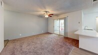 Located at 301 N Roadrunner Pkwy in Las Cruces, NM, this single-floor, one-bedroom, one-bathroom unit offers a well-organized and functional layout. The living area is finished with plush wall-to-wall carpeting, a textured ceiling, and a ceiling fan with integrated lighting. A sliding glass door connects the living space to a private outdoor balcony, which features light wood plank decking and horizontal-plank siding, providing a comfortable spot to enjoy the New Mexico surroundings.

The galley-style kitchen is bright and efficient, lined with white cabinetry, light-colored countertops, and light vinyl plank flooring. Stainless steel appliances, including a full-size refrigerator, complete the space, while a window allows for natural light.

The bedroom is a comfortable, carpeted retreat with its own ceiling fan, a large window that brings in natural light and views of the outdoors, and direct access to the hallway and closet. The bathroom features a clean, white vanity with ample cabinet storage, a large mirror, and a tub-shower combination, maintaining a bright and tidy aesthetic throughout.

A dedicated hallway connects all areas of the unit, contributing to a logical and easy-to-navigate floor plan. This unit combines practical design with comfortable finishes in a convenient Las Cruces location.