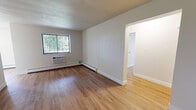 Located at 900 Macbeth Drive in Monroeville, PA, this two-bedroom, one-bathroom unit offers a well-organized single-floor layout designed for comfortable everyday living. The living room features warm hardwood flooring, a window with vertical blinds that brings in natural light, a baseboard heating system, and a wall-unit air conditioner, creating a functional and inviting gathering space that flows directly into the kitchen. The galley-style kitchen is thoughtfully appointed with white shaker cabinetry, black hardware, granite-look countertops, light hardwood flooring, and black appliances including a range, microwave, refrigerator, and dishwasher — providing ample storage and prep space. Both bedrooms are carpeted and equipped with ceiling fans, individual wall-unit air conditioners, and baseboard heaters, ensuring year-round comfort. The spacious primary bedroom includes a closet and connects conveniently to the hallway. The second bedroom mirrors the same practical design. The bathroom features a textured wall finish and a clean, straightforward layout with a vanity and toilet. A connecting hallway ties all rooms together efficiently. Neutral tones throughout the unit create a clean, move-in-ready atmosphere suitable for a variety of décor styles.