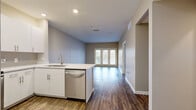 Located at 220 Summit Blvd in Broomfield, Colorado, this thoughtfully designed one-bedroom, one-bathroom residence offers a comfortable and modern living experience on a single floor. The open-concept layout connects the kitchen and living areas seamlessly, creating an inviting and functional space. The kitchen is a standout feature, equipped with stainless steel appliances including a refrigerator, electric range, and built-in microwave, complemented by crisp white cabinetry, a tile backsplash, light quartz countertops, and a peninsula with an undermount sink — ideal for casual dining or food preparation. Rich hardwood-style flooring runs throughout the main living areas, adding warmth and continuity. The living room is bright and airy, anchored by a set of French doors that invite natural light and provide outdoor access. The spacious bedroom is finished with plush carpet, a ceiling fan, and a well-sized window. The bathroom features a clean, modern vanity with a white countertop, a large mirror with accent lighting, and a walk-in closet nearby. Additional conveniences include in-unit laundry, a hallway with ample storage, and two closets, making this residence as practical as it is attractive.