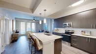 Located at 2900 W Hamlin Rd in Rochester Hills, Michigan, this thoughtfully designed 2-bedroom, 4-bathroom residence offers a modern living experience across a well-appointed single floor. The open-concept kitchen and living area serves as the heart of the home, anchored by a large center island with a white quartz countertop, bar seating, and an undermount sink. Dark espresso cabinetry, stainless steel appliances — including a range, microwave, and refrigerator — and light wood-look flooring give the kitchen a sleek, contemporary feel. Pendant lighting above the island adds a refined touch. The adjacent living area benefits from floor-to-ceiling windows and patio access, filling the space with abundant natural light. The primary bedroom features a tray ceiling, plush carpeting, a bank of wide windows, and a spacious walk-in closet with custom shelving. Bathrooms are clean and modern, with private water closets featuring floating wood shelves for added storage. A dedicated laundry area and three closets provide excellent organization throughout. The private patio extends the living space outdoors, rounding out this well-equipped Rochester Hills residence.