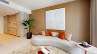 Located in the heart of Miami's Brickell district, this thoughtfully designed one-bedroom, one-bathroom residence offers a refined urban living experience with premium finishes throughout. The open-concept living room is bathed in natural light from expansive floor-to-ceiling windows that frame impressive city skyline views. Curved, contemporary furnishings, a warm terracotta and neutral color palette, and a textured accent wall anchored by a large-scale art piece create an inviting and sophisticated ambiance. The kitchen is outfitted with light wood cabinetry, a striking marble slab backsplash, sleek quartz countertops, integrated Bosch appliances, and brushed gold fixtures — a combination of elegance and functionality. The generously proportioned primary bedroom features floor-to-ceiling windows with additional city views, a geometric-patterned accent wall, and a built-in wood-paneled closet with ample shelving. The bathroom is finished with large-format tile, a soaking tub with a glass enclosure, and coordinating brushed gold hardware that ties the space together. Light wood-style flooring runs throughout, contributing to the home's warm, cohesive aesthetic. A hallway connects all rooms, completing this well-appointed Brickell residence.