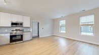 Located at 7010 Fordson Dr in Green, Ohio, this well-appointed one-bedroom, one-bathroom residence offers a thoughtfully designed single-floor layout. The open-concept kitchen and living area serves as the heart of the home, with light hardwood-style flooring that flows seamlessly throughout the main spaces. The kitchen is outfitted with crisp white cabinetry, gray subway tile backsplash, stainless steel appliances including a refrigerator, range, microwave, and dishwasher, along with track lighting and a window that invites natural light over the sink. The living area is bright and airy, featuring two windows that bring in ample daylight and provide outdoor views. The bedroom is a standout feature, boasting vaulted ceilings, plush wall-to-wall carpeting, a ceiling fan, and multiple windows on two walls that fill the space with natural light. A dedicated closet provides practical storage. The bathroom is finished with gray shaker-style cabinetry, granite countertops, a glass-enclosed shower, and a window for natural ventilation and light. Clean neutral tones and modern finishes throughout give the space a fresh, contemporary feel.