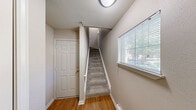 Located at 100 Lincoln Ln in Dearborn, MI, this multi-level home spans three floors and offers a well-organized layout with one bedroom and two full bathrooms. The entry-level garage provides convenient attached parking with an automatic opener. The main living floor features an open-concept kitchen and living room area with warm oak cabinetry, granite-style countertops, a double-basin sink, and white appliances including a range, microwave, and refrigerator. Track lighting illuminates the kitchen, while hardwood flooring transitions into plush carpeting in the living area. The living room is highlighted by a white-mantled fireplace and a sliding glass door that opens to a private balcony with outdoor views. A full bathroom on this level features hardwood flooring, a tiled tub-shower combo, oak cabinetry, and granite-style countertops. The upper floor hosts the spacious primary bedroom, finished with soft carpet, neutral tones, a walk-in closet, and a window that brings in natural light. A dedicated laundry room with a full-size washer and dryer adds everyday convenience. The home's neutral color palette, carpeted living spaces, and functional layout create a comfortable and practical living environment.
