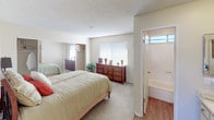 This single-floor residence is thoughtfully laid out to maximize comfort and functionality. The living room serves as the central gathering space, featuring plush carpeting, a textured ceiling, and a large window with vertical blinds that allows natural light to fill the room. The open layout connects seamlessly to the dining area, which is distinguished by a bold terracotta accent wall, ceiling fan with light fixture, and hardwood-style flooring. Two framed art pieces add a decorative touch to the dining space.

The adjacent kitchen features white cabinetry, a double sink, and essential appliances, providing a clean and efficient workspace. A hallway with hardwood-style flooring connects the main living areas to the private spaces.

The bedroom is generously sized with soft carpeting, a textured ceiling, and a mirrored sliding closet. Vertical blinds filter natural light, while a dedicated vanity area with built-in cabinetry adds a practical and elegant touch. The en-suite bathroom includes a full soaking tub and shower combination with a curtain rod, accented by a transom window that brings in additional natural light. Overall, the space presents a warm, neutral palette with cohesive finishes throughout.