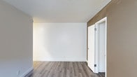 This 1-bedroom, 1-bathroom single-floor unit offers a practical and well-appointed layout designed for comfortable everyday living. The interior features warm-toned laminate wood flooring throughout, providing both durability and a cohesive aesthetic that ties the spaces together. Crisp white walls and white trim create a bright, clean atmosphere, while a textured popcorn ceiling adds a classic touch overhead. A warm, earthy accent wall introduces a layer of visual interest and contrast against the neutral palette. The bedroom is generously proportioned, offering ample room for furniture arrangement, and includes a white paneled door that contributes to the unit's tidy, uniform design. White baseboards frame each room neatly, reinforcing the clean lines present throughout. The overall ambiance is understated and move-in ready, with a neutral color scheme that lends itself well to a variety of décor styles. The single-level layout ensures easy navigation throughout, making this unit a functional and inviting living space suited for individuals or couples seeking a streamlined, low-maintenance home.