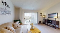 Located at 4333 Parkway Village Dr in Grove City, Ohio, this single-floor residence offers a thoughtfully designed layout with a warm and inviting atmosphere throughout. The living room serves as the heart of the home, featuring plush carpeting, a vaulted ceiling, and a large sliding glass door that floods the space with natural light while providing direct access to a private outdoor balcony. The kitchen is equipped with stainless steel appliances, including a refrigerator, range, and microwave, complemented by honey-toned wood cabinetry and durable hardwood-style flooring. An adjacent dining nook with windows on two sides creates a bright and cozy space for everyday meals. The primary bedroom features a neutral accent wall, plush carpeting, and generous closet space with natural light from a dedicated window. A second bedroom offers its own window with natural light and ample floor space, suitable for a variety of uses. The full bathroom includes a dual-sink vanity with warm wood cabinetry, a large mirror, hardwood-style flooring, and a separate shower-tub combination. Throughout the home, a cohesive neutral color palette, textured ceilings, and consistent finishes contribute to a comfortable and functional living environment.