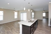 This single-story space is designed with a practical, open layout that promotes comfortable living throughout. The main living area features wood-look plank flooring, neutral beige walls, a ceiling fan with integrated lighting, and a sliding glass door alongside a window that invites natural light. The open-concept kitchen flows seamlessly from the living space and is equipped with rich, dark espresso cabinetry, granite-style countertops, stainless steel appliances including a range, over-the-range microwave, and refrigerator, plus a central island with pendant lighting above.

The bedrooms are carpeted and each include ceiling fans with lighting. The primary bedroom is generously sized with multiple windows, while additional bedrooms offer comparable comfort. A large walk-in closet with wire shelving and carpeted flooring provides ample storage.

Two full bathrooms serve the space, each featuring dark vanity cabinetry with granite-style countertops and wood-look flooring. One bathroom includes a walk-in shower, while the other offers a shower-tub combination. An adjacent laundry area with hookups rounds out the functional layout of this well-appointed space.