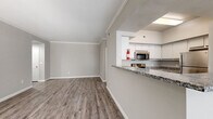 Located at 15100 Ella Blvd in Houston, TX, this single-story, 2-bedroom, 1-bathroom home offers a well-designed layout with consistent wood-look flooring and neutral gray tones throughout. The open living room is bathed in natural light through large windows with blinds and connects seamlessly to the kitchen via a pass-through counter, creating an airy, connected feel. Crown molding adds a refined touch to the living and bedroom areas.

The kitchen is well-appointed with white cabinetry, granite countertops, a double-basin sink, and a full suite of stainless steel appliances, including a range, microwave, and refrigerator. The spacious primary bedroom features mirrored sliding closet doors and a ceiling fan, while the second bedroom also includes a ceiling fan and a bright window with outdoor views. Both bedrooms offer generous proportions with clean, neutral finishes.

The bathroom includes a tiled tub-shower combination with a decorative accent stripe, complemented by a granite-topped vanity and wood-look flooring. An attached garage provides additional utility space and houses the in-unit washer and dryer hookups, offering practical everyday convenience. The overall ambiance is clean, modern, and move-in ready.