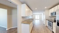 Located at 5284 Emma Grace Dr in Panama City, Florida, this single-story home offers four bedrooms and three bathrooms across a well-planned layout. The open-concept design seamlessly connects the kitchen, dining, and living areas, creating a bright and functional communal space. The kitchen is outfitted with white shaker-style cabinetry, granite countertops, a stainless steel appliance suite including a range, microwave, dishwasher, and refrigerator, plus a pantry for additional storage. Light-toned luxury vinyl plank flooring runs throughout the home, complementing the neutral gray and beige wall palette and giving the interiors a clean, modern feel. The living room features recessed lighting and access toward the rear of the home, where a patio and a fenced backyard provide outdoor space. The spacious primary bedroom is served by its own bathroom, while three additional bedrooms share access to the remaining two bathrooms, each featuring tub-shower combinations. A dedicated laundry room houses a full-size washer and dryer. The attached garage offers ample space for vehicles or storage. The home is situated in a newer residential neighborhood with a well-maintained streetscape.