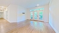 Located at 3318 Mowbray Ln, Unit 6, Cincinnati, OH 45226, this 1,240 sq ft single-floor unit offers 3 bedrooms and 2 bathrooms with a clean, modern aesthetic throughout. Light hardwood-style flooring runs continuously across every room, creating a cohesive and bright interior. The open-concept living room features French doors with transom windows that flood the space with natural light and provide access to an outdoor balcony with tree-lined views. A pre-mounted TV bracket is included on the living room wall. The kitchen is well-appointed with white shaker cabinetry extending to the ceiling, a subway tile backsplash, stainless steel appliances including a French door refrigerator and range with microwave, a built-in wine rack, and a center island with a dark wood base and white countertop. The primary bathroom includes a glass-enclosed walk-in shower with marble-style tile, a white vanity, and wood-look flooring. The second bathroom offers a tub-shower combination with herringbone tile surround. The primary bedroom features a walk-in closet with built-in shelving and hanging rods. An in-unit laundry room houses a full-size GE top-load washer and dryer. The hallway connects all three bedrooms efficiently, and a dedicated closet provides additional storage.