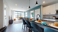 This single-floor residence at 150 River St in Hackensack, NJ presents a thoughtfully designed open-concept layout with modern finishes and a cohesive, vibrant color palette. The living area serves as a central gathering space, anchored by expansive floor-to-ceiling windows that flood the room with natural light and frame outdoor views of the surrounding Hackensack skyline. A teal accent wall adds a bold design element, complementing the wood-style flooring that extends throughout the unit.

The kitchen is outfitted with white shaker cabinetry, dark countertops, stainless steel appliances including a gas range and French-door refrigerator, and a hexagonal tile backsplash. A large island with bar seating and pendant lighting connects seamlessly to the dining area, which accommodates a round marble-top table ideal for entertaining.

The primary bedroom features floor-to-ceiling windows, a ceiling fan, a deep emerald accent wall, and access to a well-appointed bathroom with a glass-enclosed shower, built-in shelving, and a white vanity with dark countertops. A secondary bedroom offers a serene, muted blue palette with hardwood flooring and a dedicated workspace. Together, the rooms reflect a modern, design-forward aesthetic throughout.