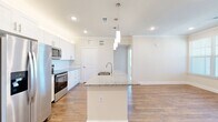 This single-floor, 2-bedroom, 2-bathroom residence offers a thoughtfully designed open-concept layout with modern finishes throughout. The kitchen serves as the centerpiece of the living area, anchored by a large island with granite countertops, an undermount sink, and stylish pendant lighting. White shaker cabinetry, a subway tile backsplash, and a full suite of stainless steel appliances — including a French door refrigerator, range, and microwave — complete the space. Wood-look flooring flows through the main living areas, complemented by crown molding and recessed lighting that enhance the clean, contemporary aesthetic. The open living area benefits from multiple windows with blinds, filling the space with natural light. Both bedrooms are carpeted and feature ceiling fans and windows with natural views, providing a comfortable, quiet retreat. Two dedicated closets offer ample storage. The bathrooms are finished with granite-topped white vanities, hardwood-style flooring, and tiled tub-shower combinations. The overall design is bright and cohesive, blending practical functionality with modern style in a well-organized floor plan.