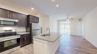 Located at 281 Salmon Brook St in Granby, CT, this single-floor, 2-bedroom, 1-bathroom residence offers a thoughtfully designed open-concept layout finished with contemporary details throughout. Light-toned hardwood-style flooring runs continuously across the entire unit, lending a cohesive and clean aesthetic to every room.

The kitchen serves as a central highlight, featuring rich dark-espresso shaker cabinetry, granite countertops, a full suite of stainless steel appliances including a refrigerator, range, and built-in microwave, and a peninsula island with an undermount sink. This kitchen opens directly into the living area, which benefits from a ceiling fan and a sliding glass door that floods the space with natural light and provides outdoor access.

The spacious primary bedroom offers generous square footage, while the second bedroom is bright and well-proportioned, each featuring large windows that bring in ample natural light. The shared bathroom is cleanly finished with a granite-topped dark vanity, a lighted mirror, and matching hardwood-style flooring. A connecting hallway ties all rooms together efficiently, completing this well-organized and modern single-level residence.
