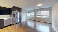 This well-appointed two-bedroom, two-and-a-half-bathroom residence offers a thoughtfully designed single-floor layout that maximizes both function and style. The open-concept living and kitchen area serves as the heart of the home, featuring warm hardwood flooring that extends throughout the main living spaces. Large windows frame urban cityscape views, filling the area with natural light and a vibrant connection to the surrounding environment.

The modern kitchen is outfitted with dark espresso-toned cabinetry, white quartz countertops, and a full suite of stainless steel appliances, including a French door refrigerator with ice dispenser, a slide-in range, built-in microwave, and dishwasher. A classic white subway tile backsplash adds a clean, contemporary contrast to the rich cabinetry.

Each full bathroom features a glass-enclosed walk-in shower with a rain showerhead and handheld fixture, large-format tile flooring, a dark wood vanity with white countertop, and a backlit mirror. The half bathroom offers a sleek vessel sink and large-format wall tile, providing a stylish and functional powder room for guests. Recessed lighting throughout the residence ensures a bright and polished ambiance across every room.