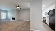 Located in Overland Park, Kansas, this single-story, 3-bedroom, 3-bathroom home offers a well-organized and functional layout with consistent design elements throughout. The living room serves as the heart of the home, featuring a classic fireplace, plush carpet flooring, a ceiling fan, and natural light streaming in through multiple windows with blinds. The space flows seamlessly toward the kitchen, which is equipped with white cabinetry featuring black hardware, white countertops, black appliances including a range and refrigerator, and durable wood-look plank flooring. Each of the three bedrooms is carpeted and includes a ceiling fan and closet. The generously sized primary bedroom connects to its own bathroom, which features a white vanity with a undermount sink, white countertops, and wood-look plank flooring. The additional bathrooms mirror this clean aesthetic, with one featuring a full tub-shower combo, white surround, and matching white cabinetry. Throughout the home, neutral gray walls, white trim, and a cohesive color palette create a calm and move-in-ready atmosphere. Built-in shelving in one area adds convenient storage options to this well-appointed single-floor home.