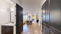 Located at 4401 Barclay Downs Dr in Charlotte, NC, this well-appointed 2-bedroom, 4-bathroom single-floor residence offers a thoughtfully designed layout that balances modern aesthetics with everyday functionality. A welcoming entrance hall with light wood flooring and striking dark-painted panel doors sets the tone throughout. The open-concept living, dining, and kitchen area forms the heart of the home, providing generous space for both relaxing and entertaining. The living room features large windows that invite natural light and offer views of the surrounding Charlotte streetscape, complemented by a ceiling fan and contemporary finishes. The primary bedroom is a spacious retreat with a textured accent wall, ample natural light, and a walk-in closet. Its en-suite bathroom is elegantly appointed with large-format tile, a glass-enclosed walk-in shower, a soaking tub, and dark-finished fixtures with gold accents. A second bedroom and additional bathrooms—featuring dark cabinetry with white stone countertops—provide comfort for guests or residents alike. Three closets and a dedicated laundry room add practical storage throughout. A private balcony overlooks the vibrant neighborhood below, rounding out this refined urban residence in the heart of SouthPark.