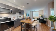 Located at 5300 E Washington St in Phoenix, AZ, this one-bedroom, one-bathroom unit offers a thoughtfully organized layout across a single floor. The entryway features light wood-tone flooring and a distinctive blue front door, setting a modern tone from the moment you step inside.

The open-concept kitchen and living area forms the core of the unit. The kitchen is equipped with stainless steel appliances—including a full-size refrigerator, electric range, and over-the-range microwave—paired with dark wood-grain cabinetry and a clean white countertop. A kitchen island with a butcher block top provides additional prep space and casual seating. The adjoining living room receives natural light through a large window with blinds and curtains, and continues the light wood-tone flooring throughout.

The bedroom offers a carpeted floor, a sizable window for natural light, a dedicated closet, and direct hallway access. Warm neutral tones give the room a calm, restful atmosphere.

The bathroom features a dark wood-grain vanity with a white countertop, an oval mirror, and a shower-tub combination. Light wood-tone flooring ties the bathroom design cohesively to the rest of the unit.