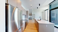 Located at 1405 Spring St NW in Atlanta's Midtown neighborhood, this contemporary high-rise unit offers a thoughtfully designed single-floor layout encompassing nine rooms. The space is defined by a clean, modern aesthetic characterized by crisp white walls, light hardwood flooring, and an abundance of natural light throughout.

The open-concept kitchen is a standout feature, outfitted with sleek gray cabinetry extending to the ceiling, stainless steel appliances including a full-size refrigerator and range, a textured tile backsplash, and a generous island with white quartz countertops and a matte black faucet. Adjacent to the kitchen, the living area is bright and spacious, complemented by a built-in wet bar with a beverage cooler and additional cabinetry.

Bedrooms are well-proportioned and bathed in natural light from dramatic floor-to-ceiling windows framed in dark metal, offering panoramic views of the Atlanta skyline and surrounding cityscape. The primary bathroom features marble-look tile flooring, a wide double-sink vanity with quartz counters, matte black fixtures, and direct access to a walk-in closet with built-in shelving. A separate powder room maintains the same minimalist design language. A private balcony further enhances the elevated urban living experience this unit provides.
