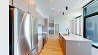 Located at 1405 Spring St NW in Atlanta's Midtown neighborhood, this contemporary high-rise unit offers a thoughtfully designed single-floor layout encompassing nine rooms. The space is defined by a clean, modern aesthetic characterized by crisp white walls, light hardwood flooring, and an abundance of natural light throughout.

The open-concept kitchen is a standout feature, outfitted with sleek gray cabinetry extending to the ceiling, stainless steel appliances including a full-size refrigerator and range, a textured tile backsplash, and a generous island with white quartz countertops and a matte black faucet. Adjacent to the kitchen, the living area is bright and spacious, complemented by a built-in wet bar with a beverage cooler and additional cabinetry.

Bedrooms are well-proportioned and bathed in natural light from dramatic floor-to-ceiling windows framed in dark metal, offering panoramic views of the Atlanta skyline and surrounding cityscape. The primary bathroom features marble-look tile flooring, a wide double-sink vanity with quartz counters, matte black fixtures, and direct access to a walk-in closet with built-in shelving. A separate powder room maintains the same minimalist design language. A private balcony further enhances the elevated urban living experience this unit provides.