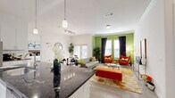 This thoughtfully designed 2-bedroom, 2-bathroom single-floor residence offers a seamless open-concept layout connecting the kitchen, dining, and living areas. The modern kitchen is a standout feature, showcasing white cabinetry, dark granite countertops, a center island with pendant lighting, stainless steel appliances, and track lighting overhead. Light wood-style flooring flows throughout, enhancing the bright and airy atmosphere. The open dining area accommodates a full-size table and is positioned near French doors that invite natural light, while the living room features crown molding and a bold accent wall. The generously sized primary bedroom includes a walk-in closet, private en-suite bathroom with dual sinks, dark granite vanity countertops, and a soaking tub. The second bedroom also offers closet access and is served by a second full bathroom with a tub-shower combination and granite vanity. Additional conveniences include an in-unit laundry area and a pantry. Throughout the residence, white walls and light flooring create a clean, contemporary aesthetic that is both functional and inviting.