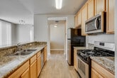 Located at 28000 S Western Ave in the San Pedro neighborhood of Los Angeles, this single-floor residence offers a thoughtfully designed layout with comfortable living spaces throughout. The galley-style kitchen is a standout feature, equipped with stainless steel appliances including a gas range, microwave, and refrigerator, complemented by warm honey-toned cabinetry and granite-look countertops. Wood-look flooring runs the length of the kitchen, which flows into a bright living area accented by warm neutral tones, plush carpeting, and vertical blinds that filter natural light. A granite-topped breakfast bar with shelving connects the kitchen to the living space, offering both functionality and an open, connected feel. The bedrooms are carpeted and bright, with large windows and sliding glass door access to a private balcony that brings in ample natural light and outdoor views. The primary bathroom is generously sized, featuring tile flooring, a soaking tub, a separate glass-enclosed shower, a granite-topped vanity, and a walk-in closet. A second full bathroom includes a tub-shower combo with a sliding glass door and a granite-topped vanity. Clean white walls and consistent finishes throughout lend the space a cohesive, move-in-ready appeal.