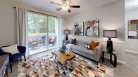 Located at 8810 Autumn Winds Dr in Raleigh, NC, this single-floor residence offers a thoughtfully designed layout with modern finishes throughout. The open-concept kitchen is a standout feature, showcasing white shaker-style cabinetry, granite countertops, stainless steel appliances, and wood-look flooring. A peninsula with bar seating bridges the kitchen to the living area, making it ideal for casual dining and entertaining.

The living room is bright and welcoming, featuring a ceiling fan and large sliding glass doors that open to a private balcony overlooking lush, mature trees — bringing in an abundance of natural light and serene outdoor views. The balcony provides a comfortable outdoor retreat with room for seating.

The bedroom is a restful haven with plush carpeting, a large window framing greenery, and a generous walk-in closet with built-in shelving and hanging rods. Neutral gray walls and soft lighting create a calm, comfortable atmosphere.

The bathroom is well-appointed with granite countertops, white cabinetry, wood-look flooring, and a tiled tub-shower combination with a classic black-and-white accent border. Additional conveniences include an in-unit laundry area accessible from the kitchen. The space combines practical functionality with contemporary style throughout.