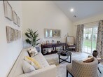 Located at 588 Bicycle Path in Port Jefferson Station, New York, this two-story home offers a refined blend of modern design and comfortable living. The main living area immediately impresses with soaring vaulted ceilings that lend an open, airy feel to the space. Large sliding glass doors flood the room with natural light while providing direct views of the outdoor greenery, creating a seamless connection between interior and exterior. The living room features light hardwood flooring that flows throughout the main level.

The kitchen is outfitted with crisp white shaker-style cabinetry, light quartz countertops, stainless steel appliances, and a tasteful mosaic tile backsplash, combining style with functionality. A convenient half bathroom on the main floor features elegant pedestal sink and a decorative gold-framed mirror.

The bedrooms are generously proportioned, with the primary bedroom benefiting from multiple large windows that bathe the room in natural light and offer pleasant outdoor views. Closet space and light hardwood flooring complete the bedroom. Additional full bathrooms are finished with clean white vanities and large-format tile flooring. The home also includes an attached garage, providing practical storage and parking. Every detail reflects a commitment to quality and modern comfort throughout.