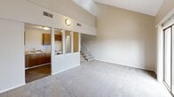 Located at 2614 S Topeka St in Wichita, Kansas, this two-floor residence offers three bedrooms and a kitchen across a well-utilized layout. The main level greets you with a generously sized living area distinguished by soaring vaulted ceilings that lend an open, airy feel to the space. The kitchen is positioned adjacent to the living area and features warm oak cabinetry, light wood laminate countertops, a stainless steel sink, and includes a dishwasher and range. Hardwood-style flooring grounds the kitchen, while plush carpet flows throughout the living and bedroom areas.

A staircase leads to the upper level, where the expansive primary bedroom serves as a true retreat. Vaulted ceilings continue here, and sliding glass doors open to a private balcony with outdoor views. The primary bedroom is equipped with multiple bifold closets, offering excellent storage. Two additional bedrooms are found on the main level — one featuring a built-in shelving ledge and high transom windows that bring in natural light, and another with its own closet and a standard window. Textured ceilings are present throughout, and neutral, warm-toned walls provide a versatile backdrop throughout the entire residence.