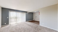 This single-floor residence offers a practical and comfortable layout across two bedrooms, one bathroom, a living room, kitchen, hallway, and entrance. The living room is a standout space, featuring plush carpeting, a bold slate-blue accent wall, and a large sliding glass door dressed with vertical blinds that invite generous natural light and outdoor views. Adjacent to the living area, the kitchen is well-appointed with white cabinetry, light speckled countertops, a stainless steel sink, and wood-look flooring — offering ample counter and storage space for everyday cooking needs.

The spacious primary bedroom is generously proportioned and features soft carpeting, neutral toned walls, and a wide sliding-door closet providing excellent storage. The second bedroom is equally comfortable, with plush carpet, a natural light-filled window, and its own closet with built-in rod and shelving. Both rooms maintain a clean, neutral palette throughout.

The bathroom features wood-look flooring, a white vanity with speckled countertop and integrated sink, and a separate water closet. A connecting hallway ties all rooms together efficiently. Overall, the space presents a clean, move-in ready environment with consistent neutral finishes and practical features throughout.