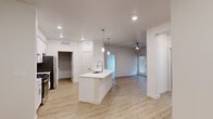 This single-floor residence offers a clean, contemporary design characterized by bright white walls, light wood-look flooring, and recessed lighting throughout. The heart of the home is an open-concept kitchen and living area, where a central island with a built-in sink and white countertop serves as the focal point. Pendant lighting hangs above the island, complementing the recessed ceiling lights, while stainless steel appliances anchor the kitchen. The layout flows seamlessly into a spacious living area equipped with a ceiling fan and a window fitted with blinds that allows natural light to fill the space.

The bedrooms are well-proportioned, each featuring ceiling fans, windows with blinds for natural light, and light wood-look flooring. At least one bedroom includes a walk-in closet with built-in shelving, providing generous storage. The bathrooms are finished in a crisp, modern style with white cabinetry, white countertops, large mirrors with vanity lighting, and a tub-shower combination with chrome fixtures. Wood-look flooring extends into the bathrooms, maintaining design consistency throughout.

A dedicated in-unit laundry room houses a full-size washer and dryer, adding everyday convenience. The overall ambiance is bright, clean, and move-in ready, reflecting a cohesive modern aesthetic.